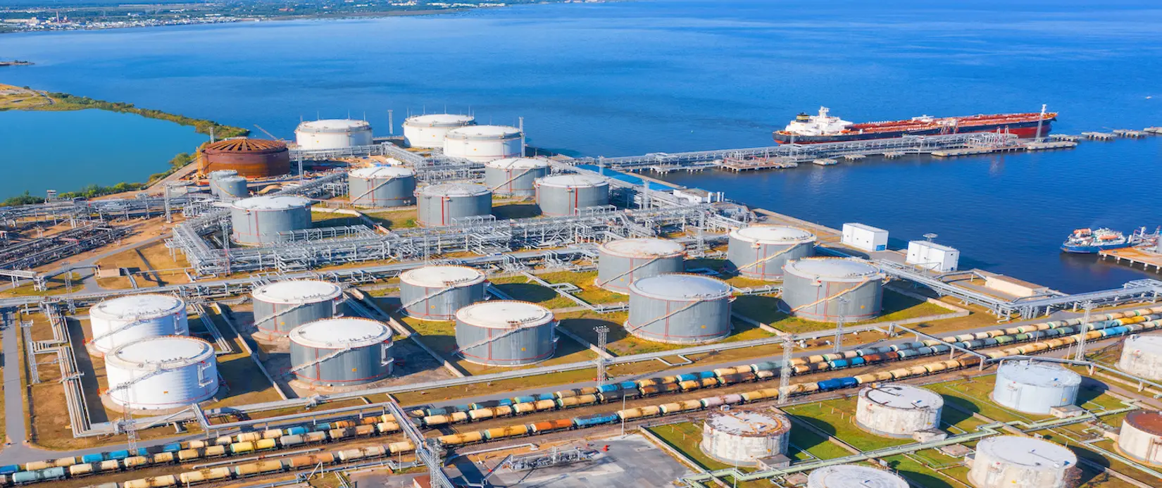 Aerial view of large fuel storage tanks at oil refinery industrial zone in the cargo seaport, and ship tanker at unloading